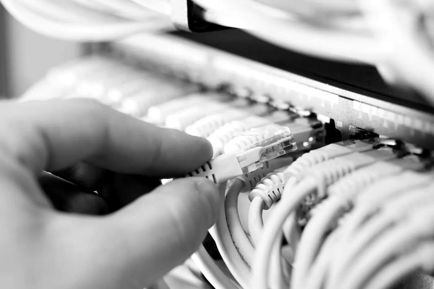 Hand plugging a network cable into a switch